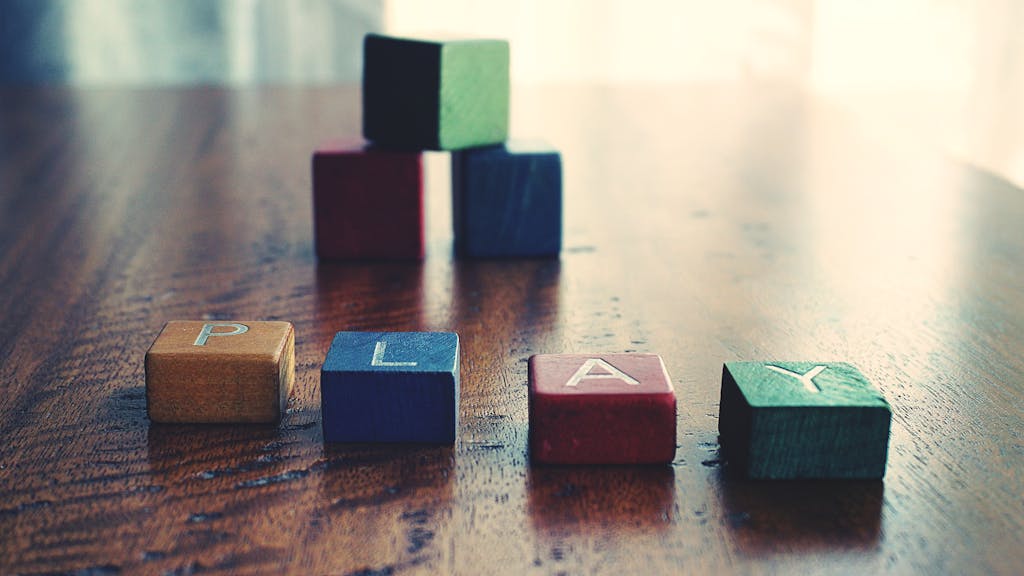 A vibrant still life of wooden alphabet blocks spelling 'PLAY' on a wooden surface.