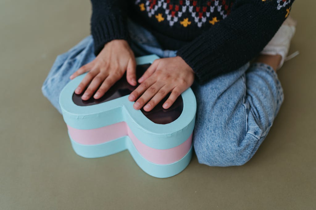 Close-up of a child's hands holding a heart-shaped box, evoking warmth and care.